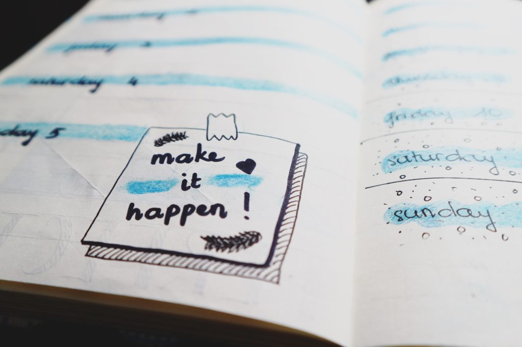Image of a daily planner with the words Make It Happen written on the right page.