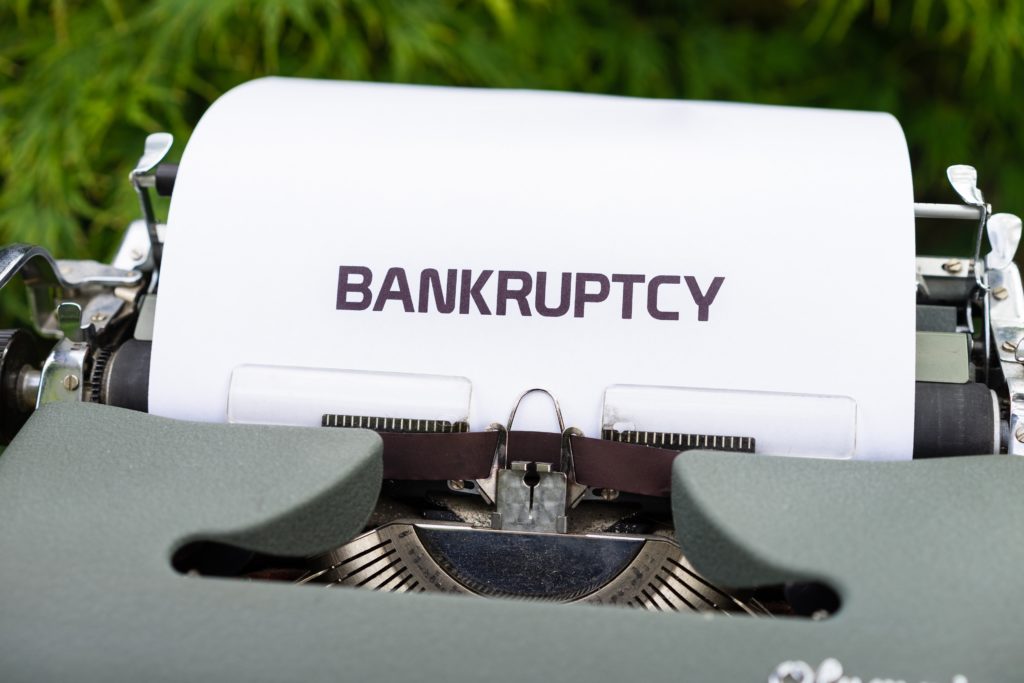Photo of a grey typewriter with a piece of paper partially inserted showing the word bankruptcy