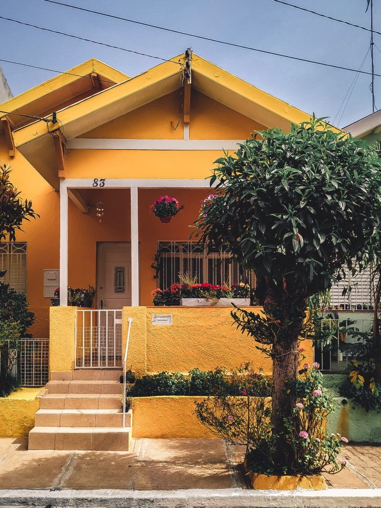 Image of a small orange house with a tree out front