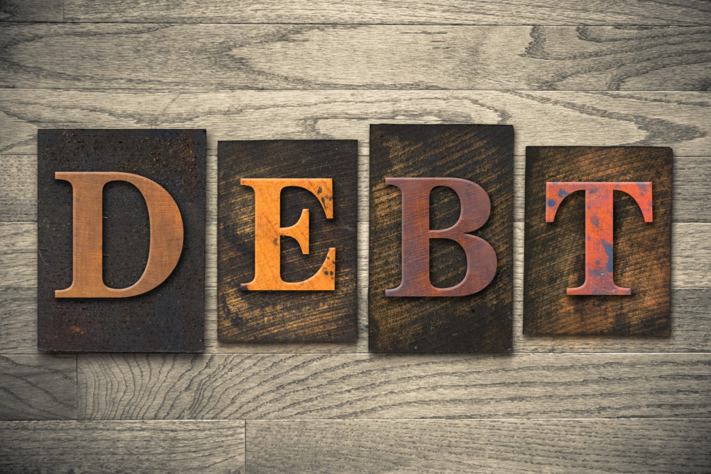 The word "DEBT" written in wooden letterpress type