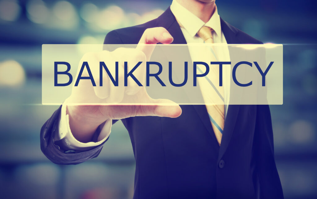 Business man holding Bankruptcy sign on blurred abstract background