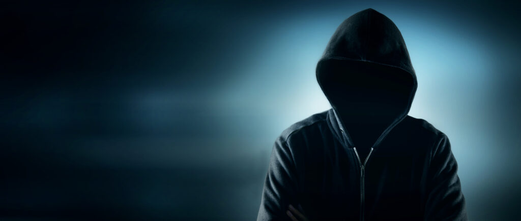 dark background with person wearing a hoodie illuminated from behind.  You cannot see their face. 